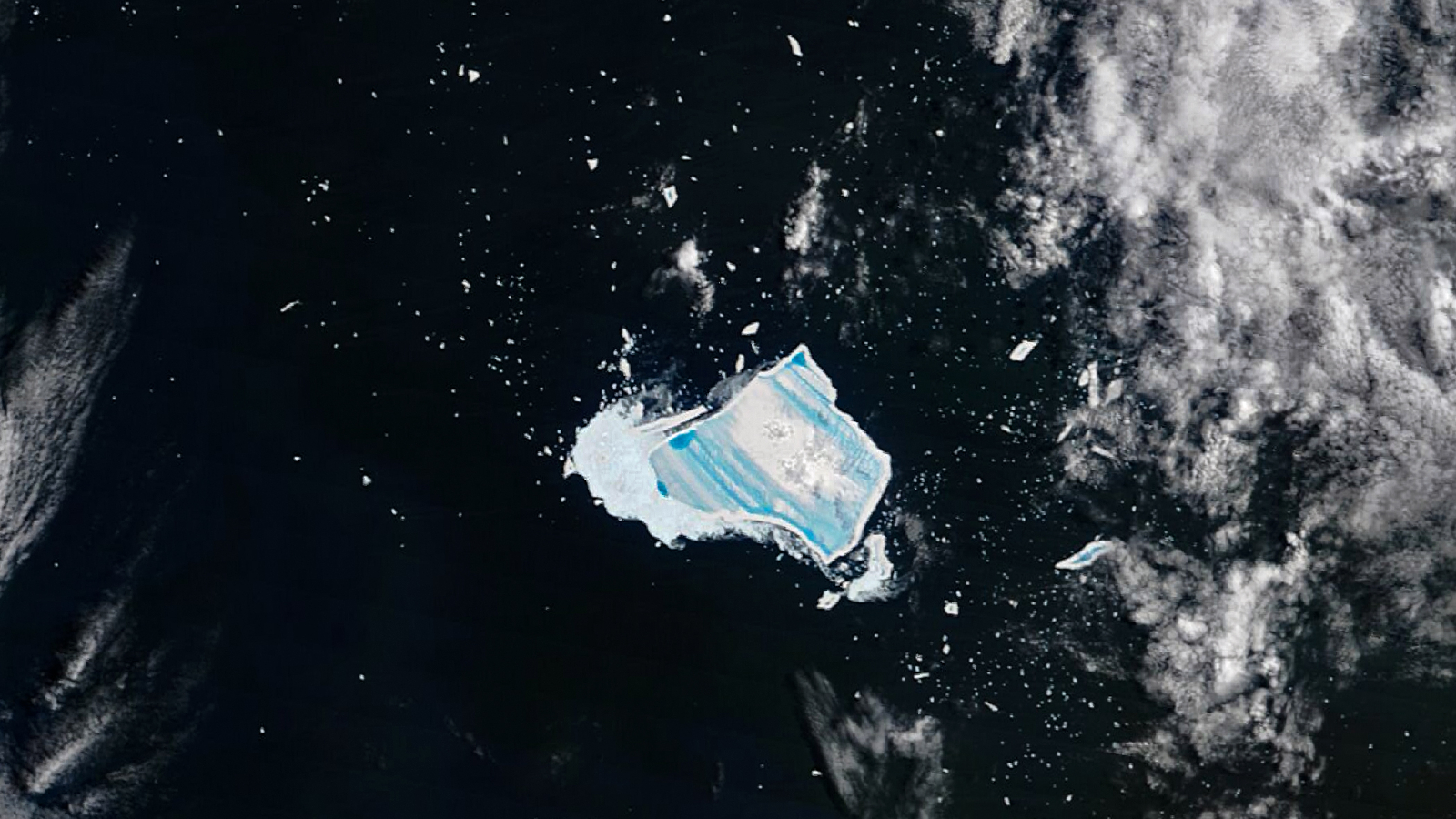 Satellite photo of an iceberg covered with vibrant blue stripes in the middle of the ocean