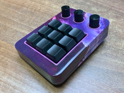 A beautiful purple galaxy-themed macro pad with nine switches and three knobs.
