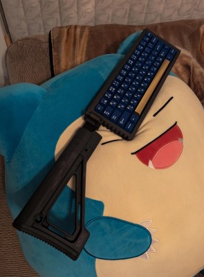 A rectangle mechanical keyboard with a foldable mil-spec stock sticking out the left side. 