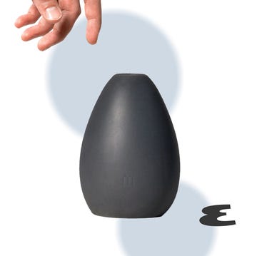 a hand reaching towards a sleek darkcolored object resembling a speaker or lamp a hand reaching towards a sleek darkcolored object resembling a speaker or lamp