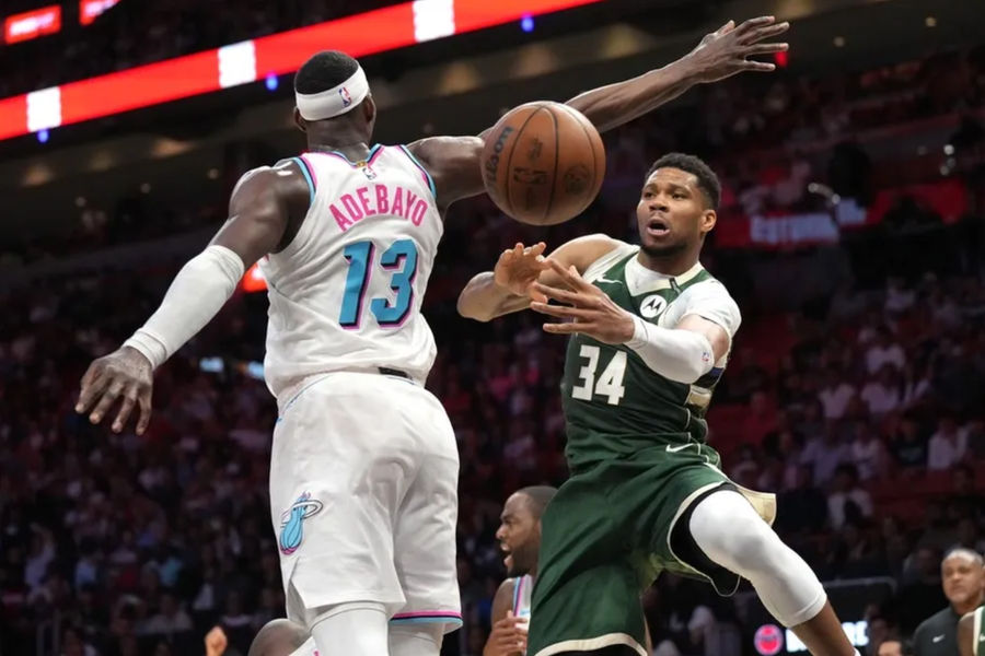 Apr 5, 2025; Miami, Florida, USA; Milwaukee Bucks forward Giannis Antetokounmpo (34) passes the ball under the arm of Miami Heat center Bam Adebayo (13) during overtime at Kaseya Center. Mandatory Credit: Jim Rassol-Imagn Images