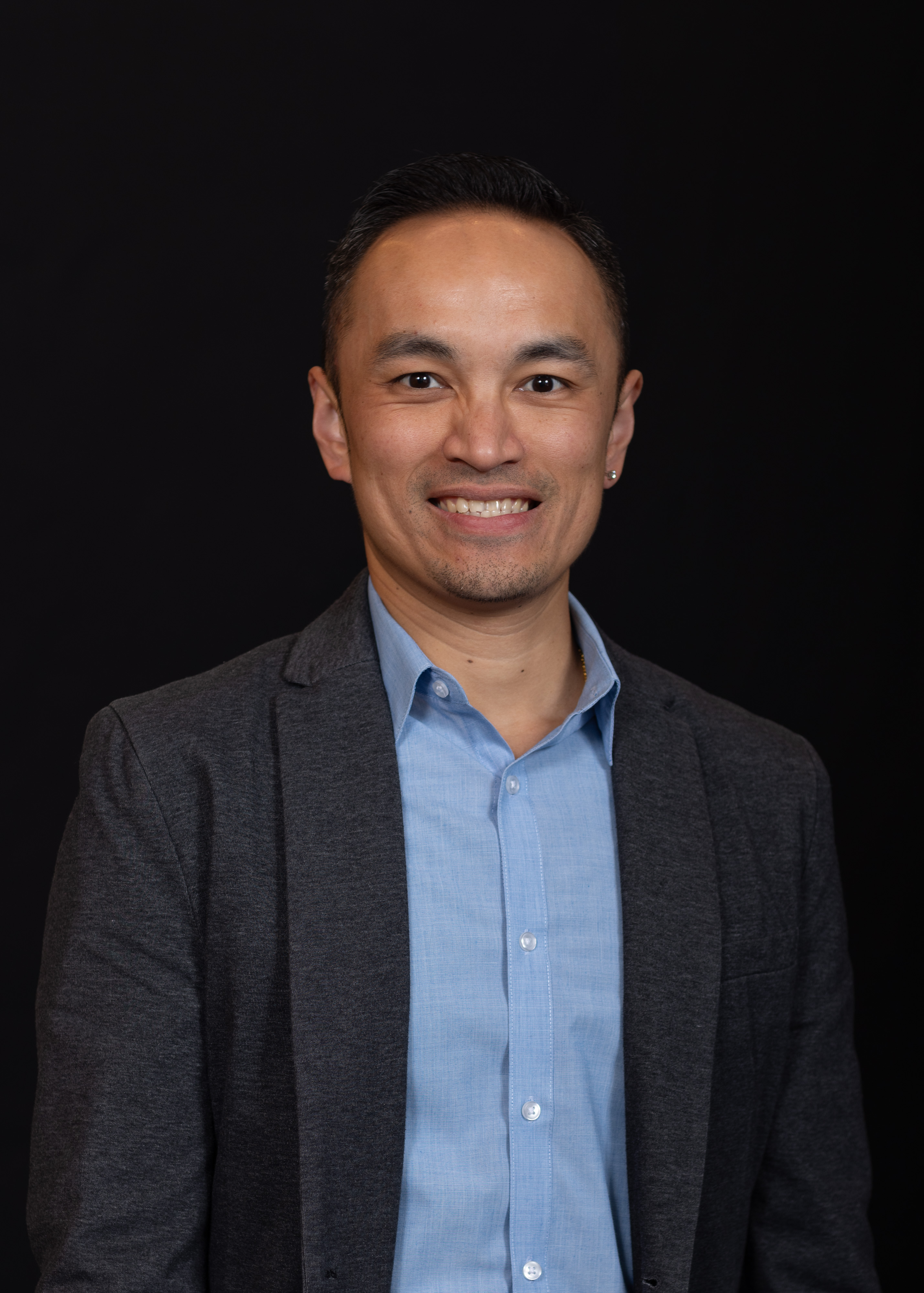 Hao Banh with short dark hair, a blue collared shirt, and grey blazer