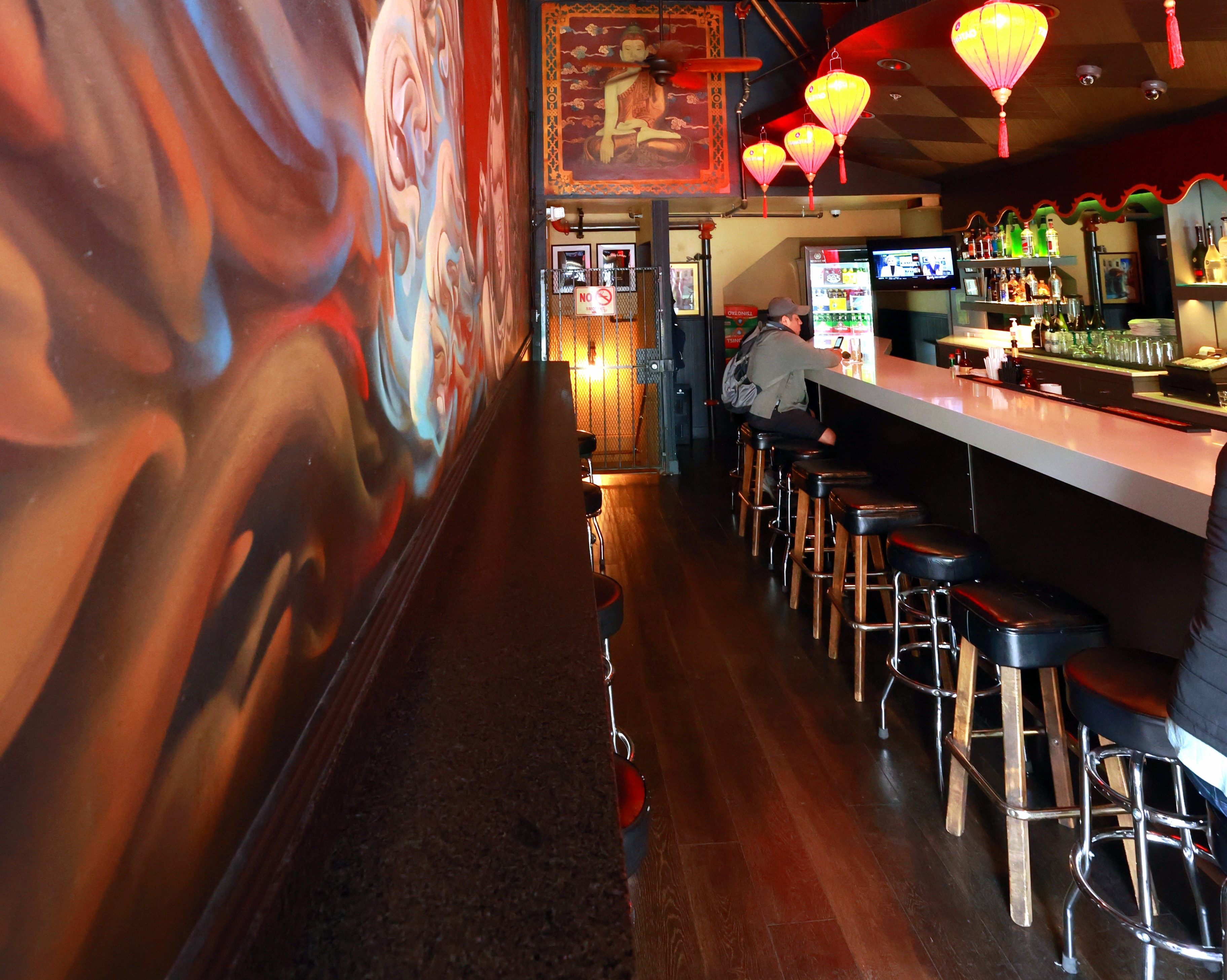 Bar with stools and one person seated in the background