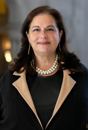 Marianne Thompson with dark medium length hair, a black blazer, and pearl necklace