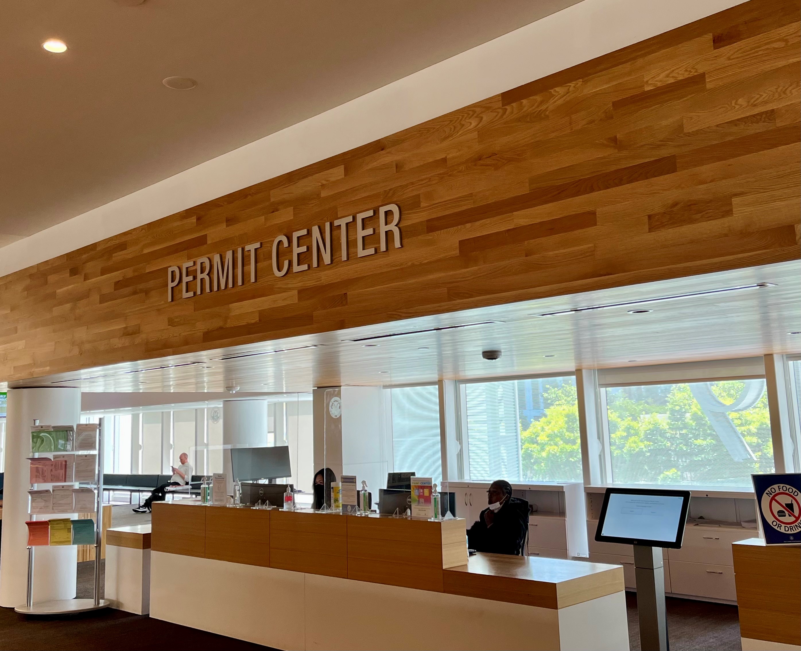 Long counter-desk with "Permit Center" written above. One person is seated at the counter.