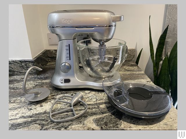 Breville Sage The Bakery Chef a silver stand mixer with accessories on a speckled kitchen counter