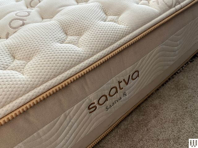 Sideview of Saatva TX a thick mattress with white top and beige trim