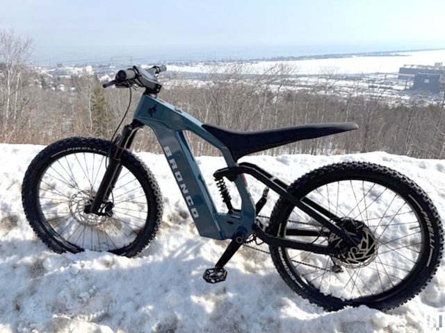 Side view of Ford Bronco Electric Bike parked in snow on top of a mountain.