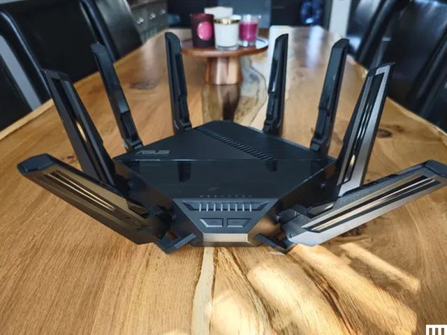 Black square device sitting on wooden table with 8 prongs sticking out 4 on each side