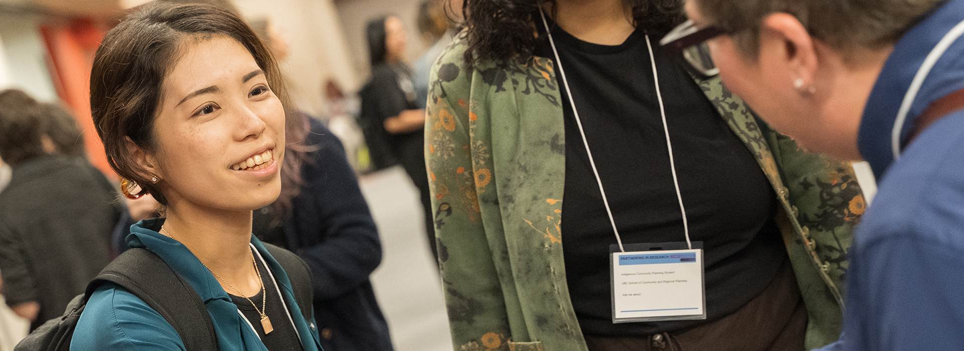 Three people networking at an event, wearing name tags around their necks
