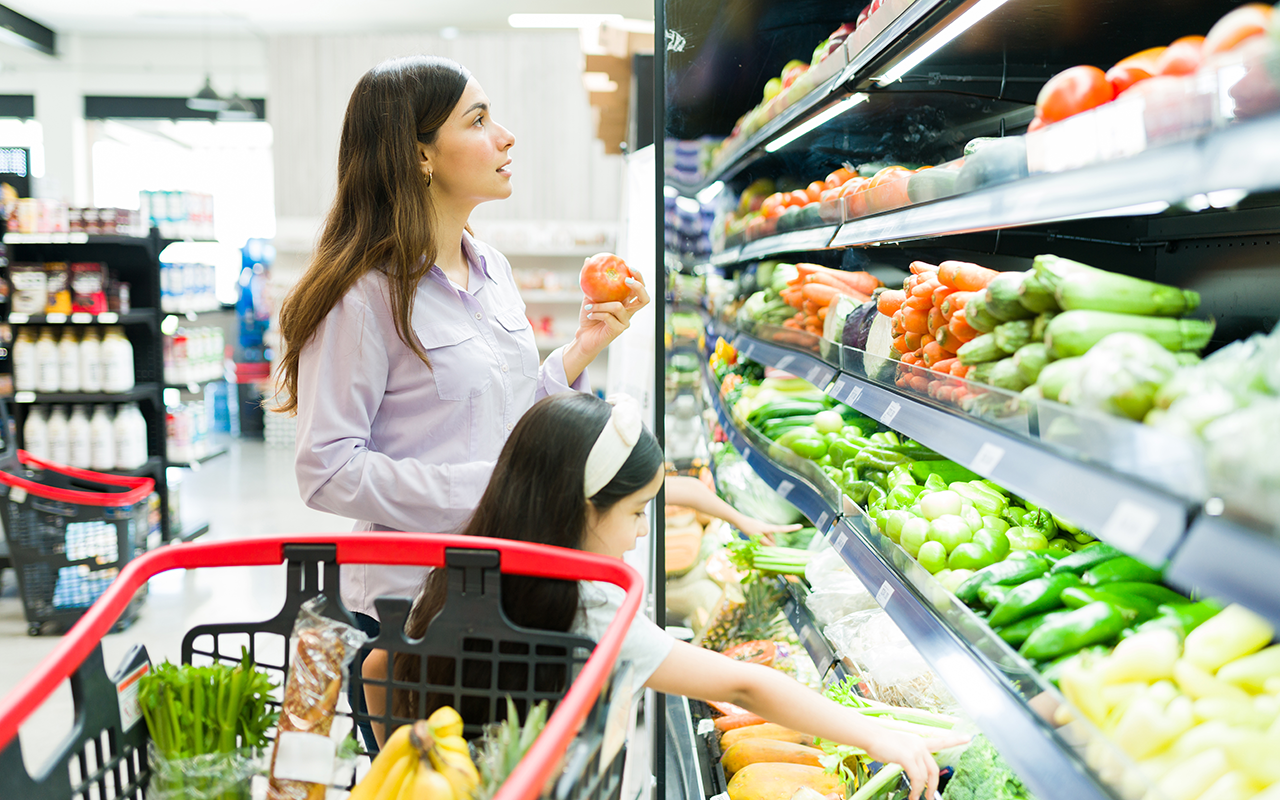 Woman and child pick vegetables from the grocery store