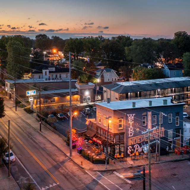 A drone shot of Bardstown Road at dusk. On the foreground building a mural reads, "The Highlands: Weird, Independent & Proud"